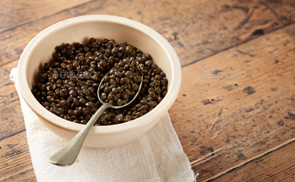 Beluga or Black Lentil in a bowl on wooden background. Empty space for text.