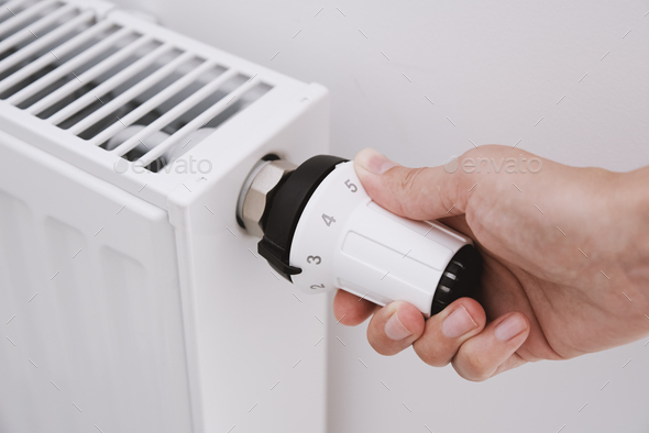 Woman hand adjusting temperature on heat radiator