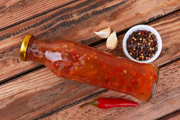 Bottle of spicy red hot sauce on wooden background