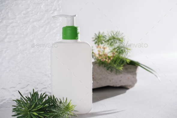 white cosmetic bottle with pump next to textured acrylic glass door and freen grass and leaves