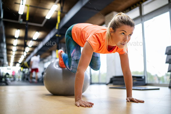 Happy fit woman exercising in a gym to stay healthy Stock Photo by nd3000