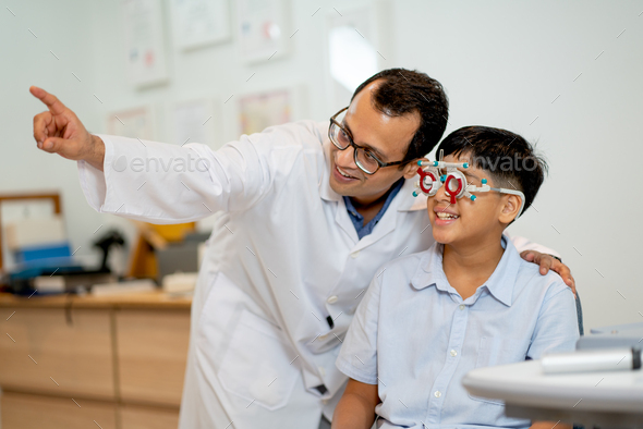 Ophthalmologist or optical staff point to the direction for viewing of Indian boy