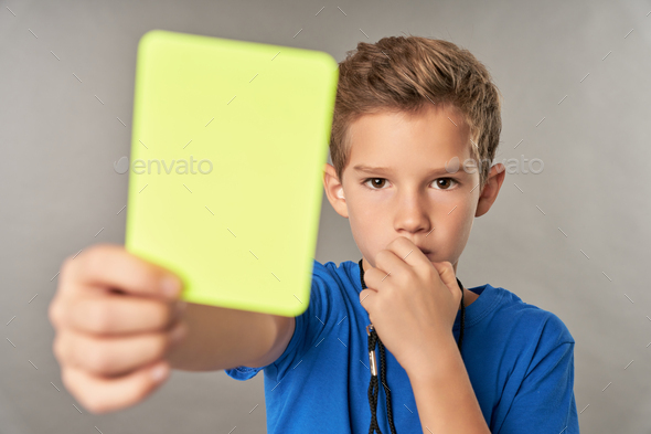 Cute boy referee holding yellow card and whistling in whistle