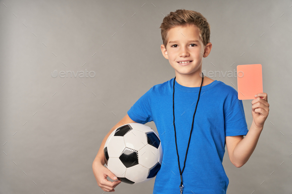 Adorable boy with soccer ball holding red card