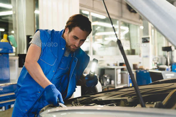 MOT. Vehicle inspection concept. Technician mechanic repairing fixing car with opened bonnet