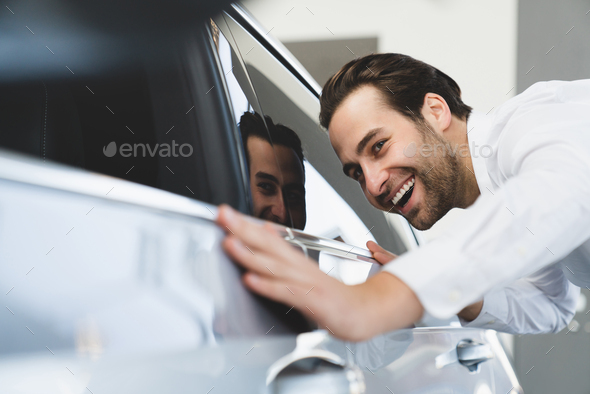 Businessman checking new car at dealer shop before buying it, dreaming about purchasing automobile