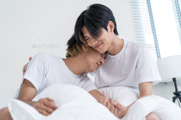 Portrait of Asian handsome gay couple sit on bed in bedroom at home.