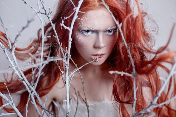 Redhead girl with long hair, a face covered with snow with frost. White eyebrows and eyelashes in