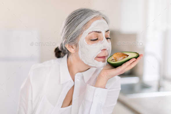 gray haired lady with white clay cosmetic mask on her face
