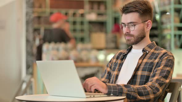 Professional Young Man Using Laptop in Cafe  alt