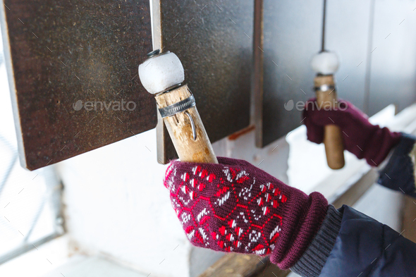Hands in mittens with ornaments close-up on bell tower or belfry beat flat bells.