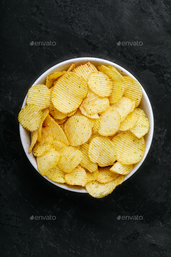 Potato chips. Crispy potato chips in bowl on a dark stone concrete background - Stock Photo - Images
