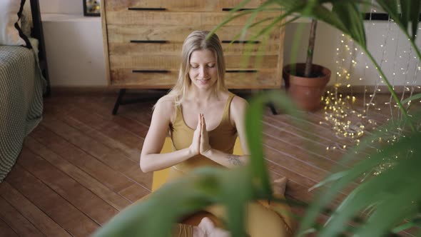 Woman Wearing Sportssuit Does Yoga on Mat in Bedroom alt