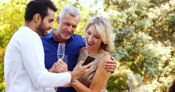 Man showing mobile phone to couple in balcony alt