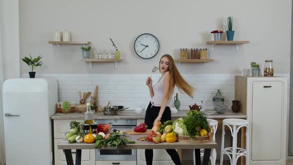 Lovely Vegan Girl with Long Hair Dancing and Singing in Modern Kitchen. Raw Vegetable Food Diet alt