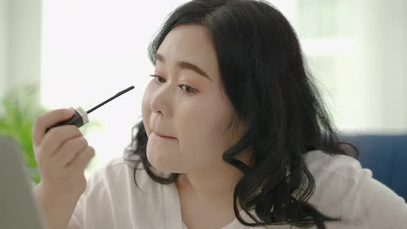 plus size Asian woman bloggers sitting are online to review cosmetic products via social media.