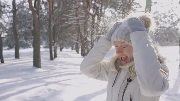 Portrait of Cute Girl in Winter Clothes Crushes Snow From Hat and Warms Hands in Warm Mittens alt