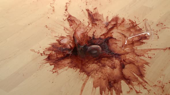 Dropping glass of red wine and breaking on wooden floor, Slow Motion alt
