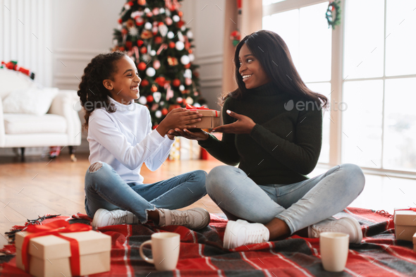 Portrait of happy black family celebrating Christmas giving present - Stock Photo - Images