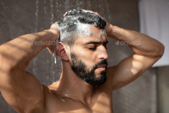 Handsome condifent young Arabic male model enjoying taking hot shower - Stock Photo - Images