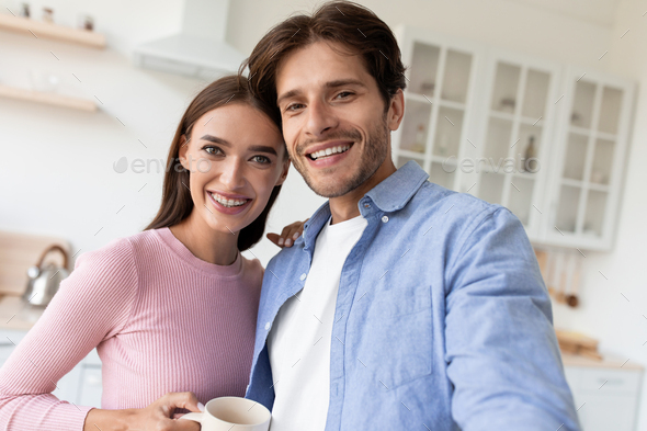 Happy millennial european woman and guy with cups, drink coffee in morning and take selfie - Stock Photo - Images