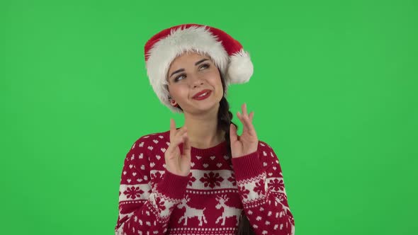 Portrait of Sweety Girl in Santa Claus Hat Is Daydreaming and Smiling Looking Up. Green Screen alt