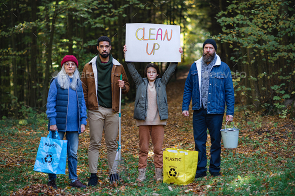 Diverse group of irritated activists ready to clean up forest, holding banner and looking at camera - Stock Photo - Images