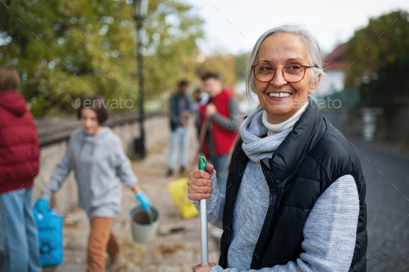 Senior woman volunteer with team cleaning up street, community service concept - Stock Photo - Images