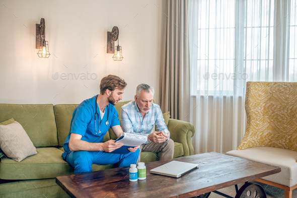 Geriatric physician prescribing a dietary supplement to the male patient - Stock Photo - Images