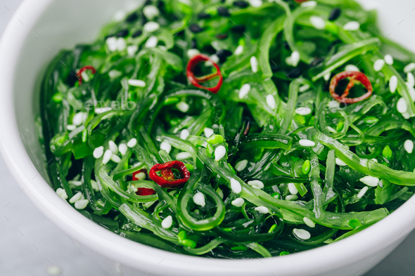 Seaweed Salad with sesame seeds in bowl on gray concrete stone background - Stock Photo - Images
