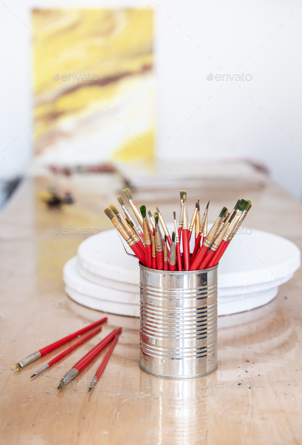 A metal can with a set of brushes for painting in an art workshop. Stock  Photo by puhimec