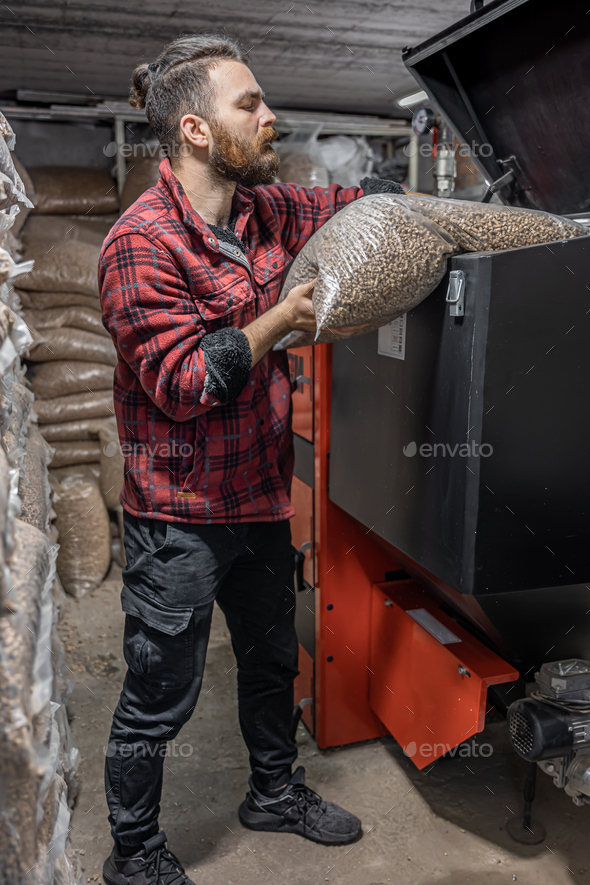 The man loads the pellets in the solid fuel boiler, working with biofuels.