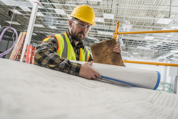 Construction Worker Looking Inside Building Blueprints - Stock Photo - Images