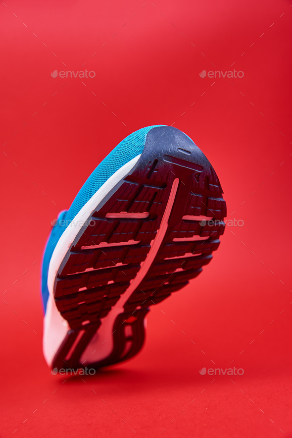 Blue running sneaker on red background, close up