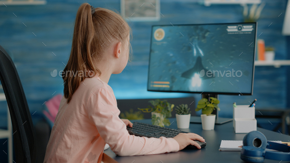 Young girl playing video games on computer after online school Stock Photo  by DC_Studio