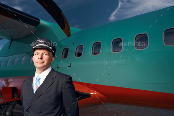 Man pilot posing for photo outside before airplane