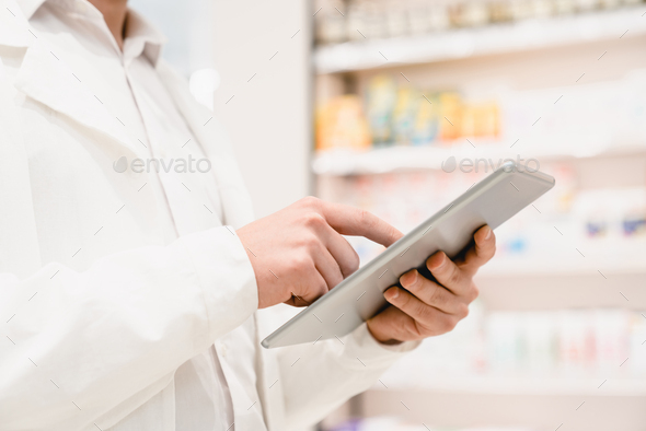 Pharmacist using tablet for checking expiration date, side effects, active substance of drugs