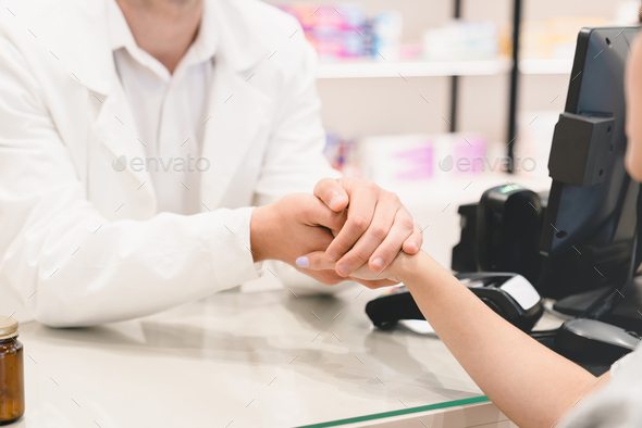 Pharmacist doctor supporting buyer, listening attentively to her medical complaints at cash desk