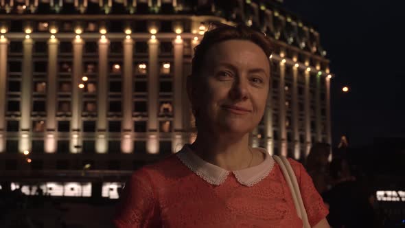 Shooting a Portrait of a Woman Against the Backdrop of a Beautiful Night Building