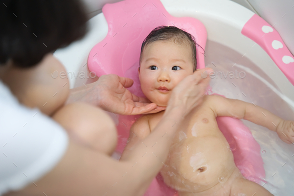 Little young cute Asian baby has been taking a bath in bathtub and washing by her mother. - Stock Photo - Images