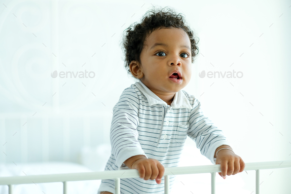African American child boy stand near bed rail and he look happy and innocent