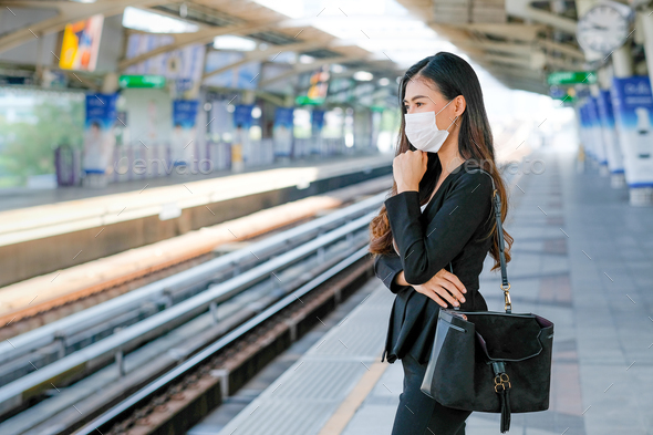 Business girl with hygiene mask stand on platform for waiting the sky train during go to work - Stock Photo - Images