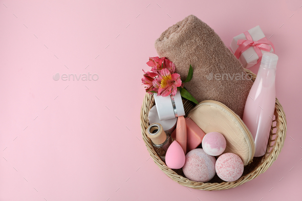 Wicker basket with cosmetics on pink background