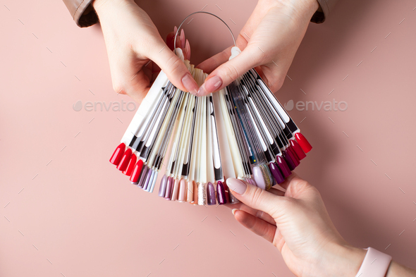 A manicurist holds a palette of gel polish flowers and the client chooses a color.