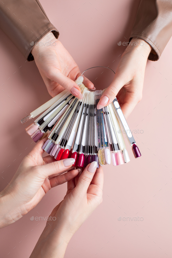 A manicurist holds a palette of gel polish flowers and the client chooses a color.