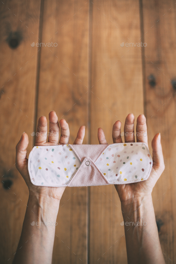 reusable cloth menstrual pad on women\'s hands. zero waste concept. vertical