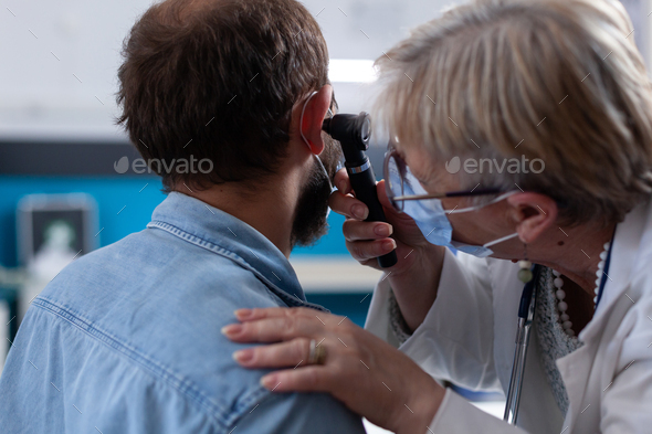 Close up of specialist using otoscope to do ear examination with patient