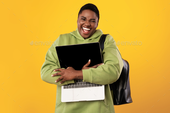 Excited Plus-Sized Black Lady Embracing Laptop Computer Over Yellow Background