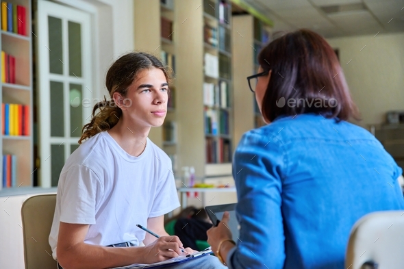 Woman school psychologist teacher talking and helping student, male teenager