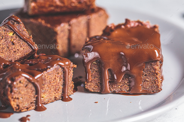 Vegan brownie squares with dark chocolate on gray plate, close-up. Vegan dessert concept.